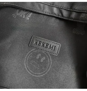 Close-up of black nylon backpack detail featuring leather brand tag and white smiley face