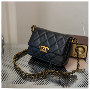 Detail of black quilted leather shoulder bag with gold chain strap and luxury hardware