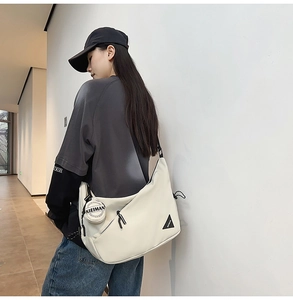 Detail of white dumpling crossbody bag with mini round pouch and black woven strap