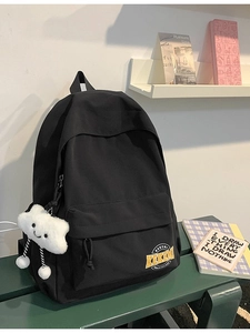 Minimalist black school backpack with plush cloud pendant on green metal bench