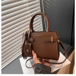 Gros plan d'un sac à main rétro en cuir marron foncé avec détails métalliques dorés
