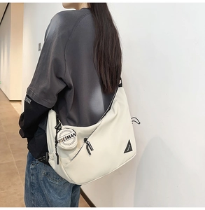 Detail view of white crossbody dumpling bag featuring a round detachable coin purse