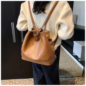 Damen Rucksack aus braunem PU-Leder mit Kordelzug über einem hellen Strickpullover