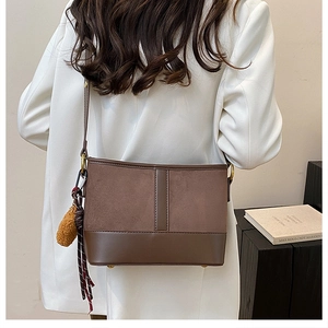 Detailed side view of the brown bucket bag featuring stylish tassels and suede leather finish