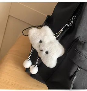 Close-up of cute plush white cloud charm with smiling face hanging on a black backpack