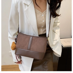 Detail of coffee brown bucket bag featuring textured suede contrast and chic bear charm