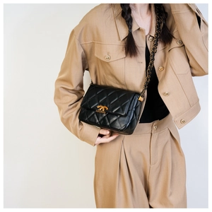 Close-up of black quilted leather crossbody bag with gold chain strap and metal clasp