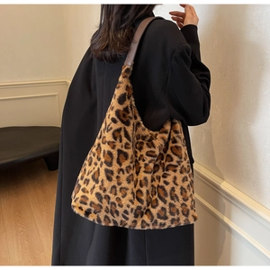 Borsa tote leopardata in peluche con tracolla in pelle marrone indossata a spalla