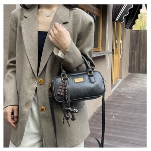 Close-up of black leather pillow bag with gold hardware and cute cat charm detail