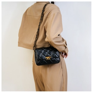 Quilted black chain bag on model showing shoulder carry and gold clasp detail