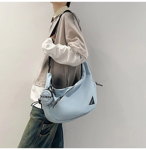 Close-up of light blue dumpling bag with a small round pouch and adjustable strap