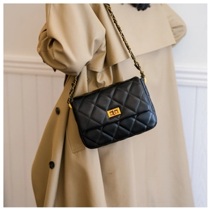 Close-up of black quilted leather shoulder bag with gold turn-lock and chain strap