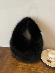 Elegante schwarze Kunstpelz-Hobo-Handtasche auf Holztisch für Herbst und Winter Mode
