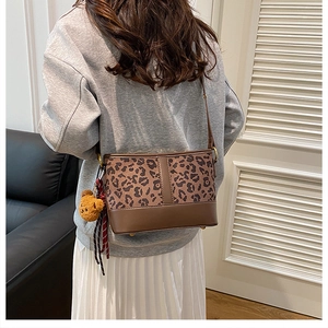 Detail of leopard print bucket bag with bear charm worn with casual outfit