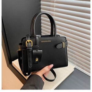 Détail de la texture cuir mat et boucle métallique dorée sur un sac à main noir