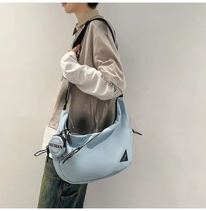 Detail of light blue nylon dumpling bag with adjustable strap and coin purse charm