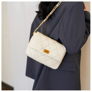 Quilted beige shoulder bag with gold turn-lock and chain strap shown on a model