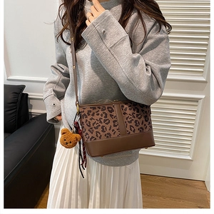 Detail of leopard print bucket bag featuring brown leather trim and cute bear charm