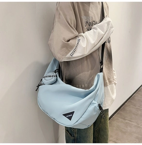 Detailed side view of a light blue large dumpling crossbody bag with a round coin purse
