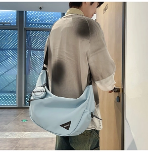 Detail of light blue nylon dumpling bag with a detachable round coin purse and black logo