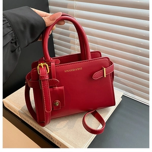 Détail du sac à bandoulière rouge avec logo doré et boucles latérales élégantes