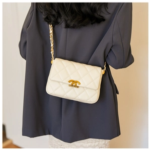 Quilted white shoulder bag with gold chain strap shown on a model in a blue blazer