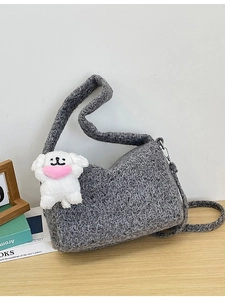 Grey knit crossbody tote bag with cute plush puppy charm on a wooden table setting