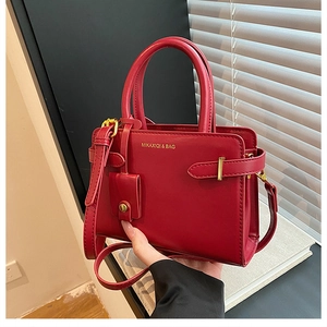 Détail du sac à main rouge en cuir avec marquage doré, mini pochette et garniture