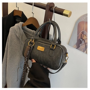 Detail of vintage black boston bag with gold metal plate and cute animal pendant