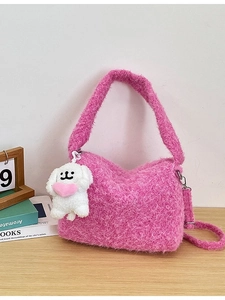 Chic pink fuzzy shoulder bag with cute puppy plush charm on a wooden desktop