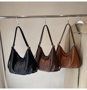 Detailed view of three soft faux leather hobo bags with embossed logo on metal hangers