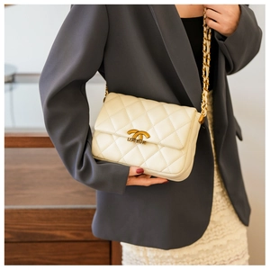 Close-up of beige quilted leather bag with gold chain and metal clasp detail