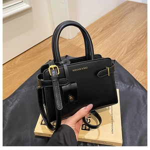 Gros plan du sac en simili cuir noir mat avec ferrures dorées et logo de la marque