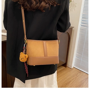 Detail view of leopard bucket bag with soft plush bear charm and sleek golden buckle