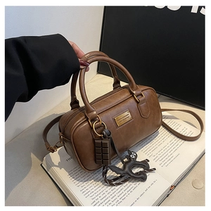 Detail of vintage brown leather pillow bag with gold plate and cute bag charms