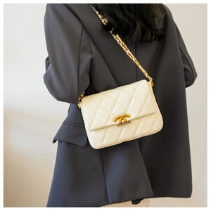 Detail of cream quilted shoulder bag with gold chain strap and metal turn-lock closure