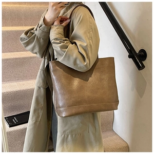 Nahaufnahme der braunen Leder-Tragetasche kombiniert mit einem klassischen Trenchcoat