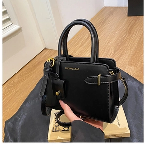 Gros plan d'un cabas en cuir noir avec logo doré, bandoulière et détails dorés