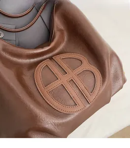 Detail of soft brown leather tote showing embossed double-B logo and fine texture