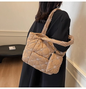 Detail of quilted tote bag with floral embroidery and matching mini pouch accessory