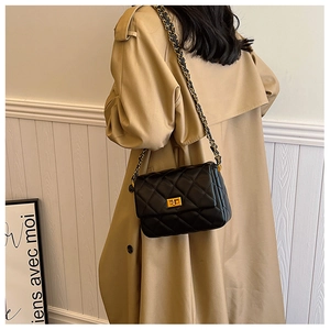 Chic quilted black shoulder bag with gold hardware shown on a trench coat model