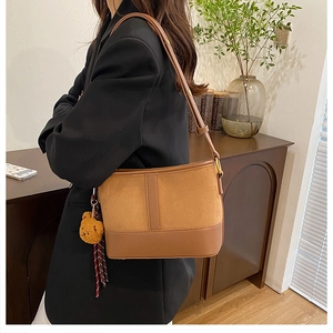 Detail view of brown leopard bucket bag with soft plush bear charm on adjustable strap