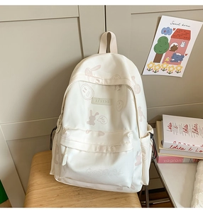Detailed view of cream nylon backpack with purple cartoon bunny prints and side pocket