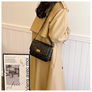 Detail of black quilted leather shoulder bag with gold chain strap and turn-lock closure