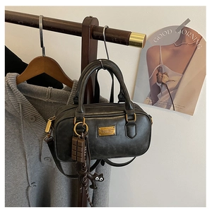 Detail of black vintage pillow bag with gold plate and cute cat pendant on a wooden hanger