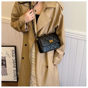 Detail of black quilted leather shoulder bag with gold chain strap and turn-lock
