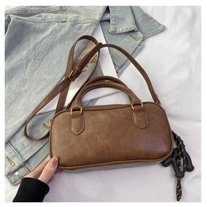 Detailed macro view of the vintage brown matte leather texture and letter bag pendant