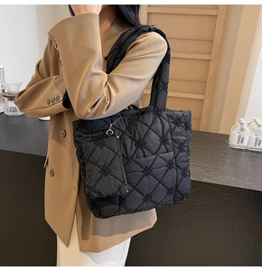 Detail shot of black quilted tote bag with floral embroidery and hanging mini pouch