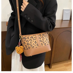 Leopard print bucket bag with brown leather base and cute bear charm in daily setting