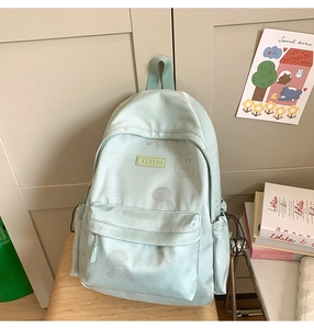 Detail of mint green backpack featuring a smile print and the KEKEMI brand rubber logo